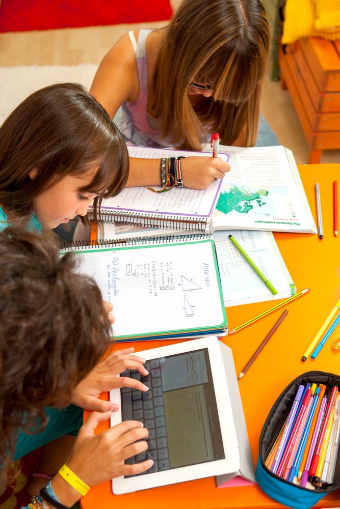 Three,Teenage,Girls,Busy,With,Homework,At,Desk.
